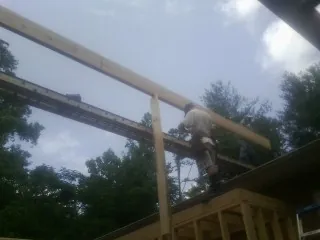 Carpenter setting a ridge beam over a new addition frame — Ice Dam Removal by Roofing Brothers in Spring Creek