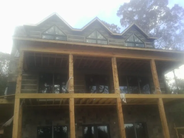 Dormers and porch framing on a large log home under construction — Roof Coating work by our crew in Spring Creek