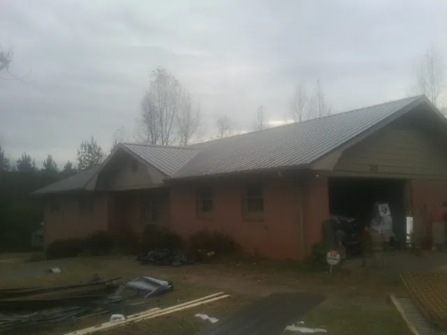 Gray metal roof on a stucco house with an attached garage in Spring Creek