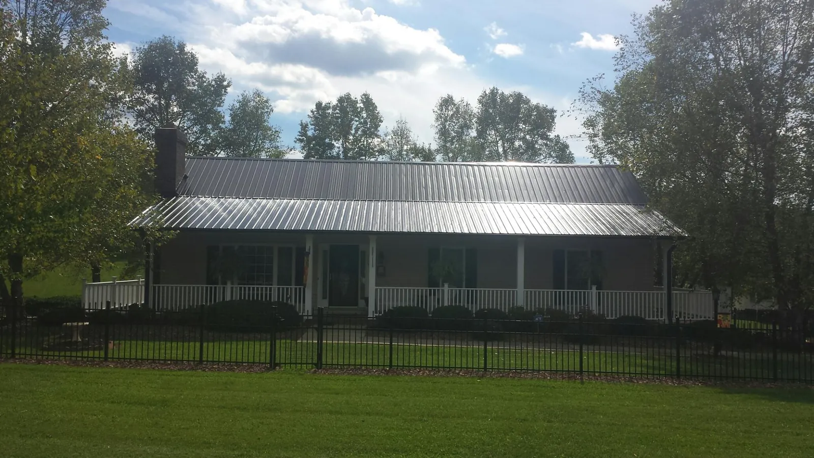 Gray metal roof on a brick ranch with a full width front porch — Gutter Guard Installation work by our crew in Spring Creek